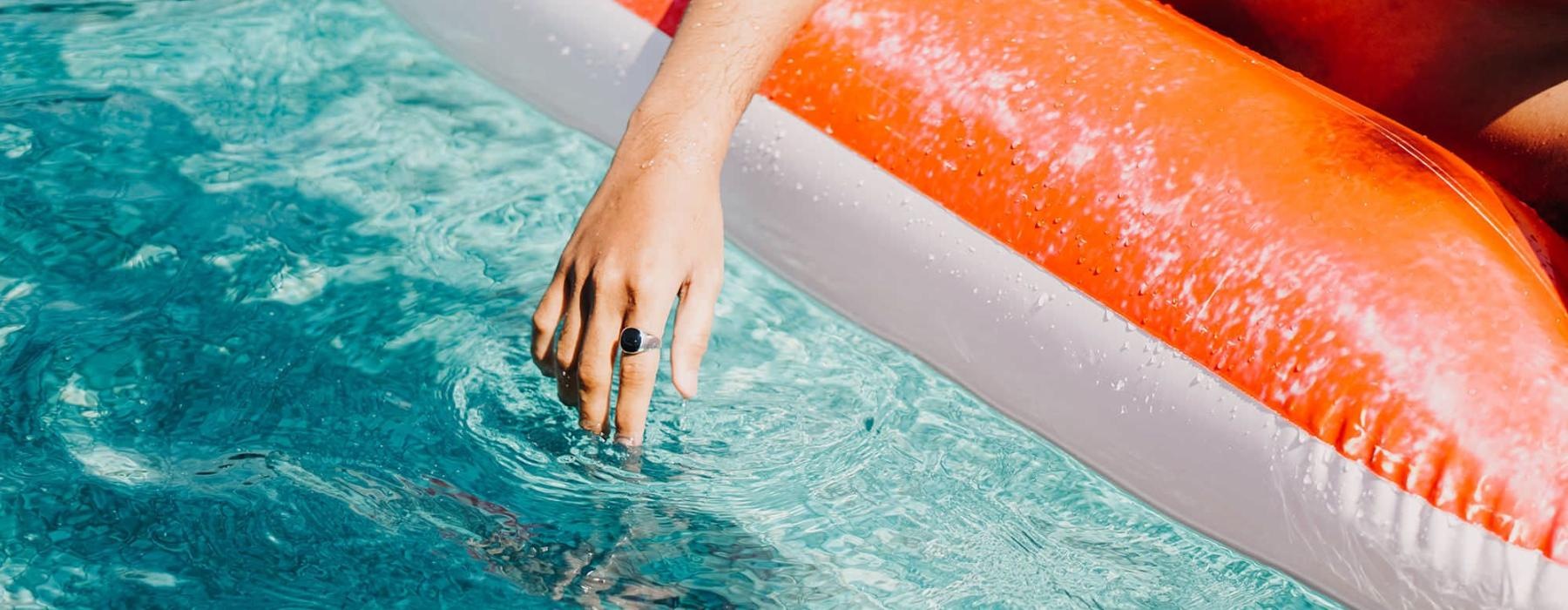 woman dangles her hand in the pool as she floats in an inflatable vessel